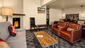 Ein gemütliches Wohnzimmer mit Kamin, Ledersofa und Couchtisch aus Holz.