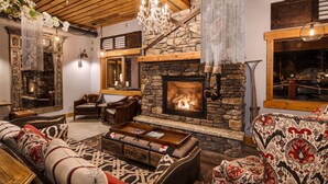 Una sala de estar acogedora con chimenea de piedra, muebles de cuero y una araña.