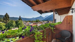 Un balcón de madera con vistas a un pueblo y montañas.
