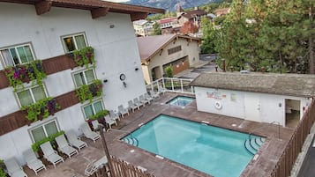 A pool area with a wooden fence, a white car, and a building with balconies.