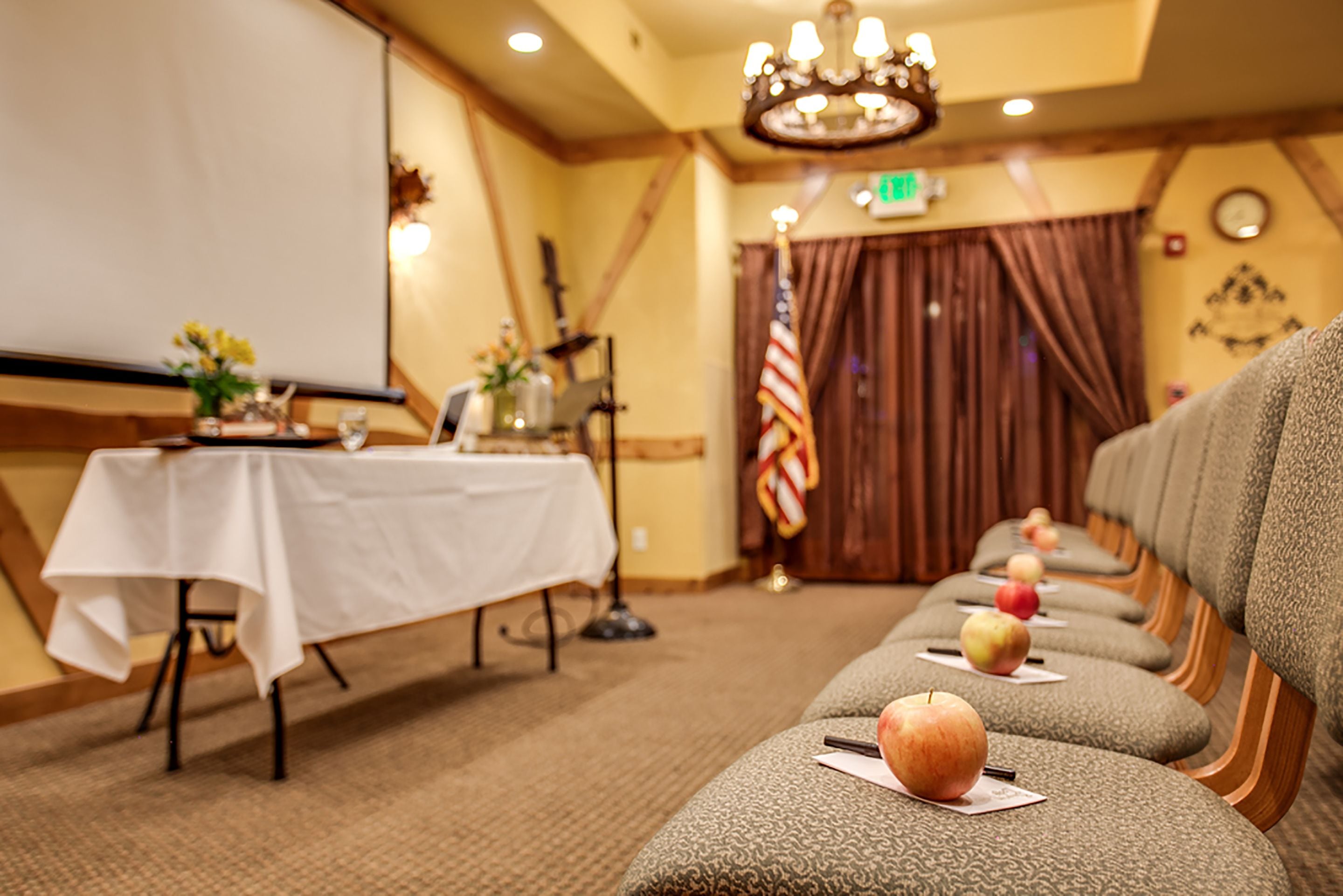 A conference room with a long table, rows of chairs, and apples on the seats.