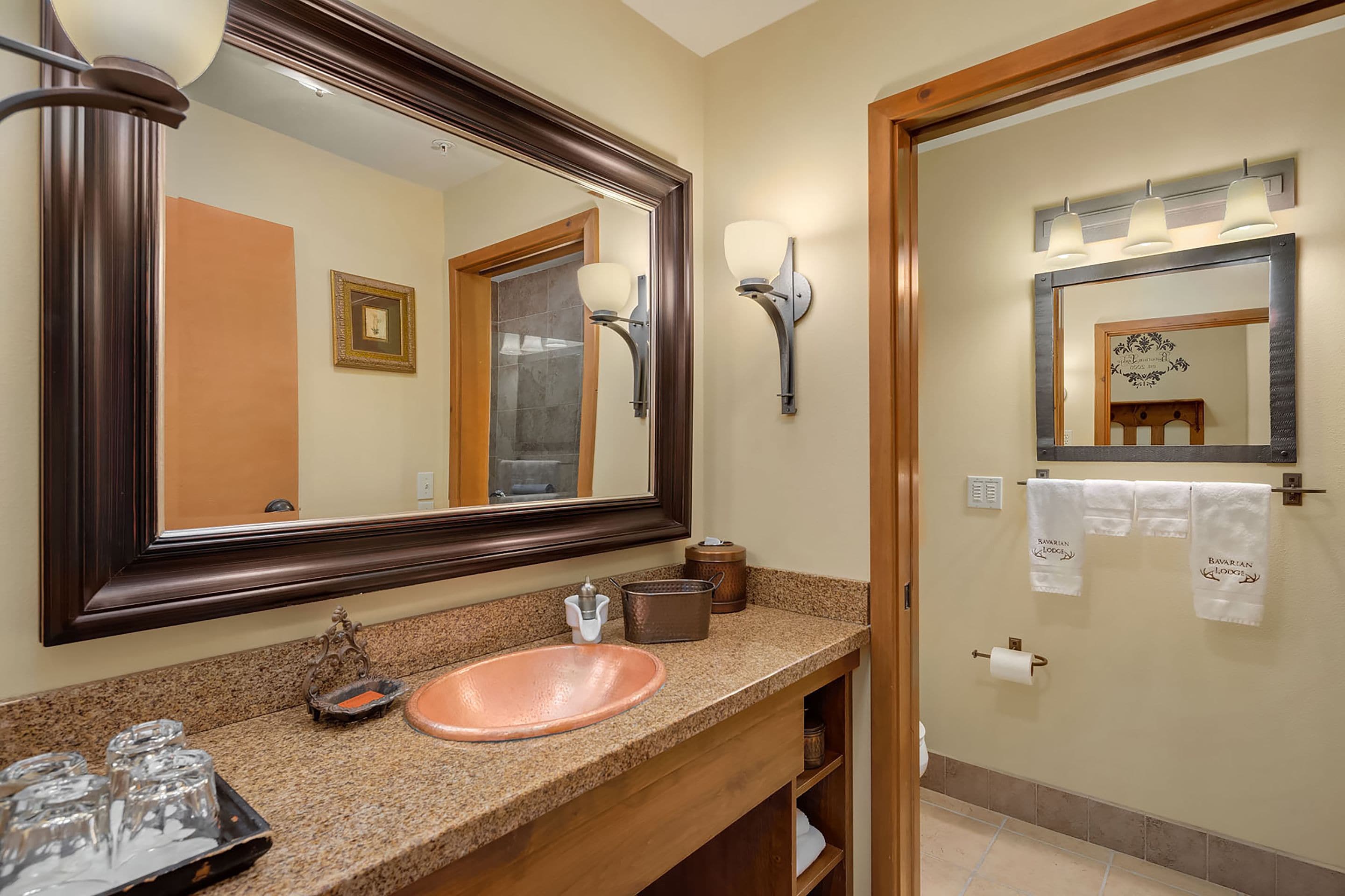A bathroom with a large mirror, a sink, and two wall-mounted lights.