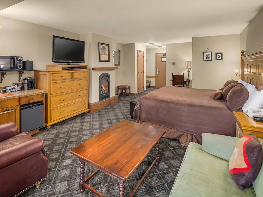 Une chambre d’hôtel comprenant un lit, un bureau avec une télévision, une cheminée et un canapé.