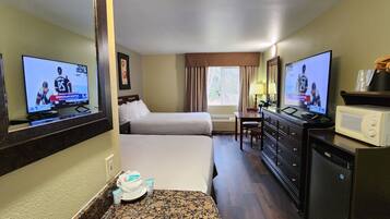 A hotel room with two beds, a television, a desk, a dresser, and a microwave.