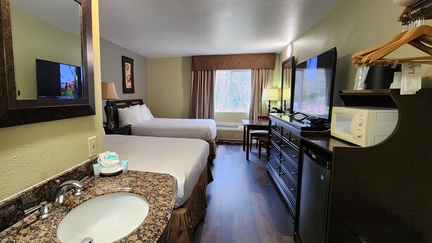 Habitación de hotel con cama, baño con lavabo y espejo, televisión y microondas.