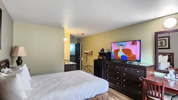 Habitación de hotel con cama, televisión, cómoda, escritorio y espejo.