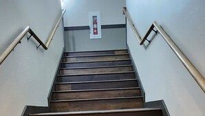 Una escalera de madera con barandillas de metal que conduce a un rellano con un extintor.