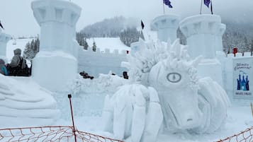 Escultura de neve com um castelo e um cavalo, cercada por uma grade.