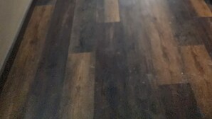 Un pasillo con piso de madera, puertas a ambos lados y letreros iluminados en la pared.