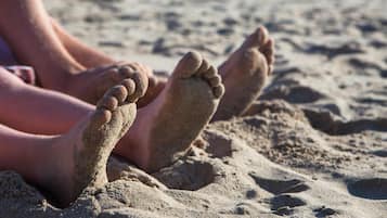 Un gros plan sur les pieds d’une personne dans le sable, ce qui suggère qu’elle se trouve sur une plage.