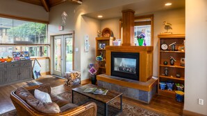 Una sala de estar acogedora con chimenea, muebles de madera y vistas al exterior.