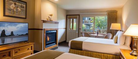 A hotel room with a fireplace, a television, a bed, a desk, and a window with a view of the outside.