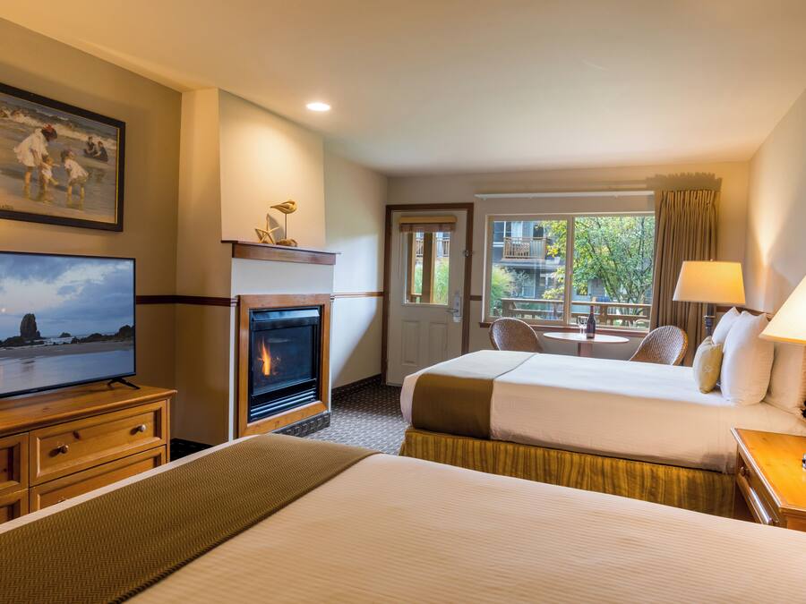 Habitación de hotel con chimenea, televisión, cama, escritorio y ventana con vistas al exterior.