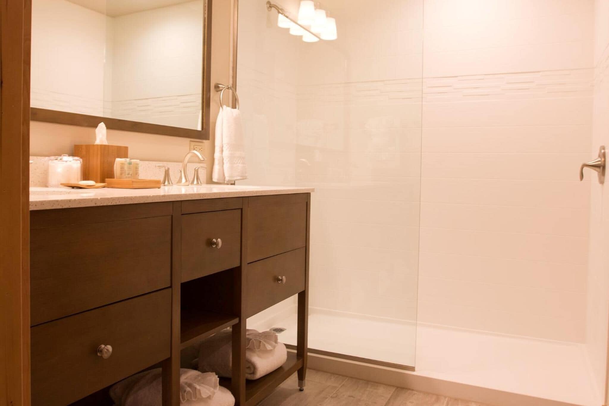 A bathroom with a wooden vanity, a mirror, a towel rack, and a glass shower enclosure.