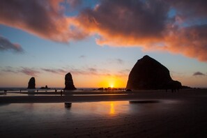 A beach with large rock formations and the sun setting in the background. - Inn at Cannon Beach (Cannon Beach)