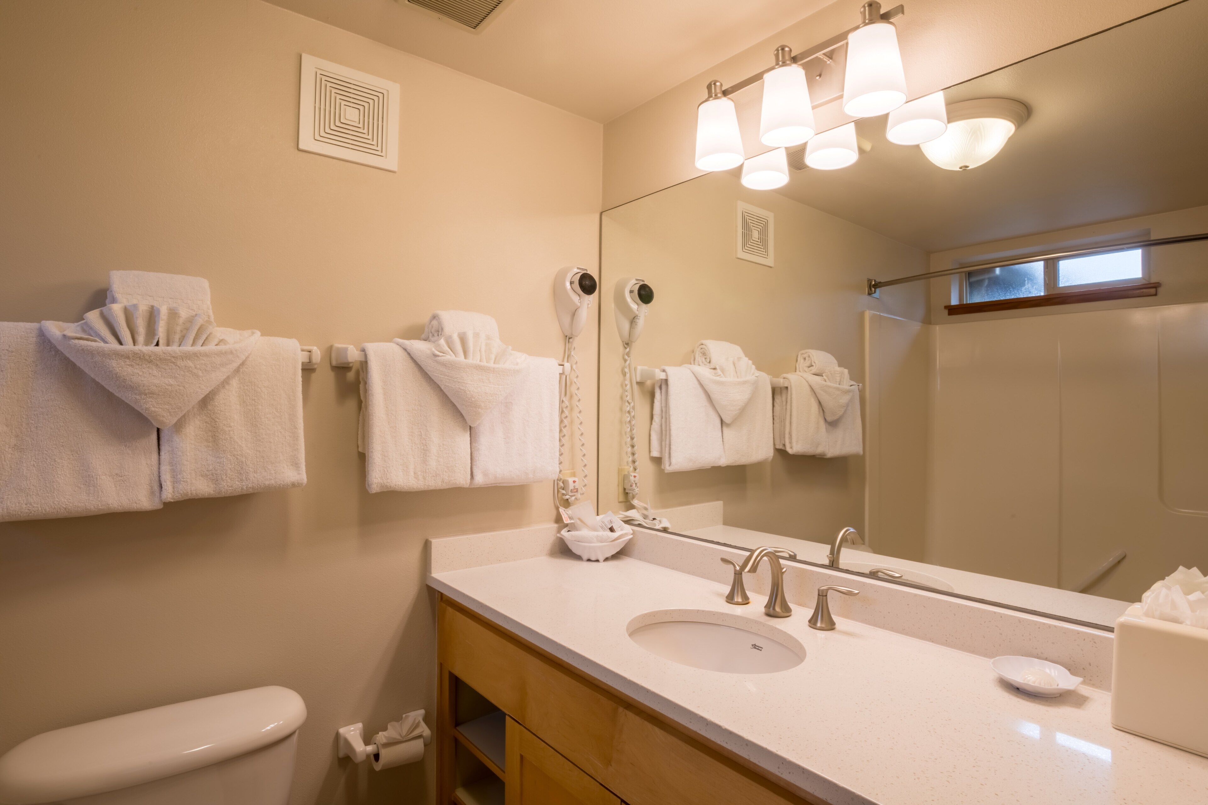 Ein Badezimmer mit Waschbecken, Spiegel, Handtuchhalter und Toilette.