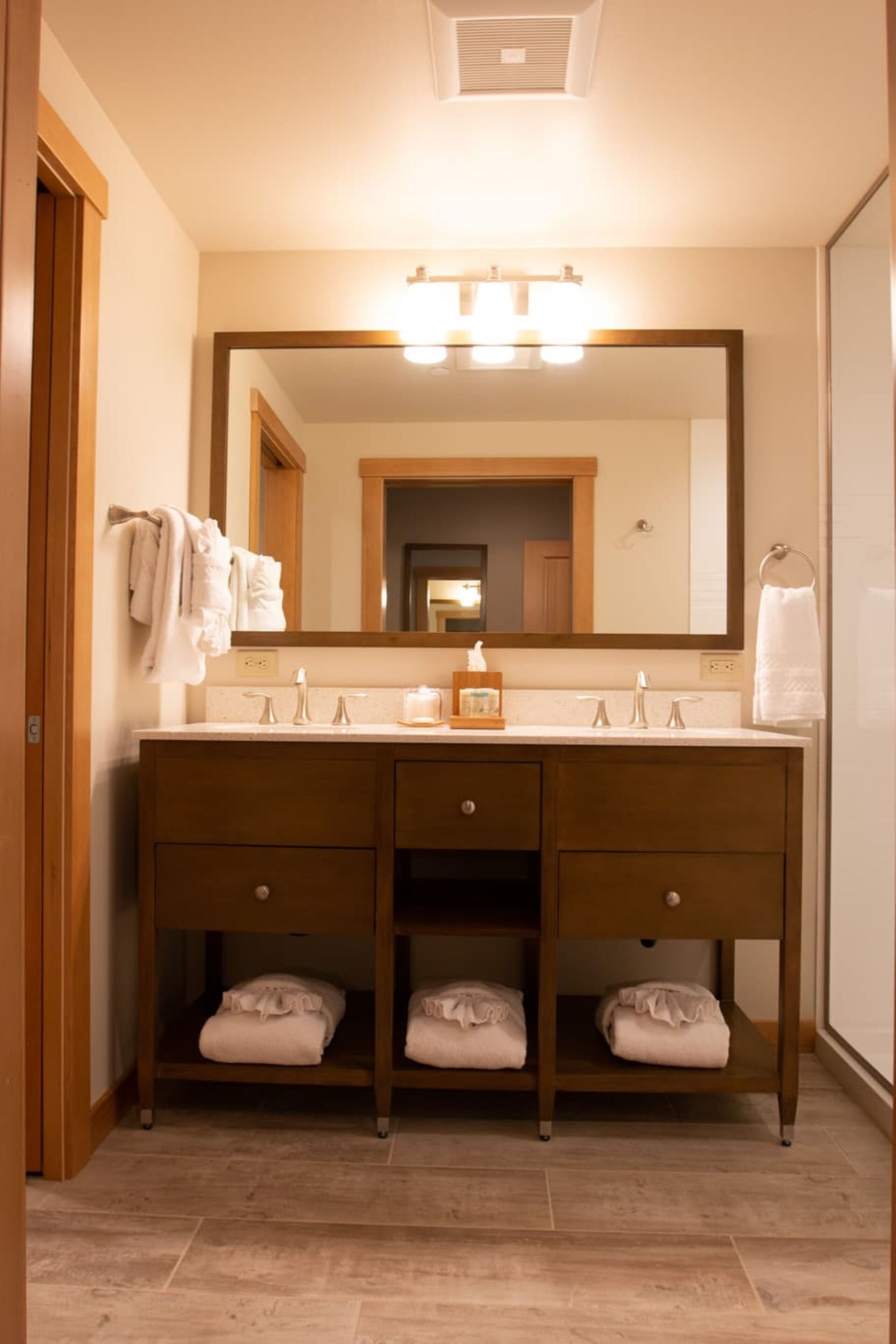 A bathroom with a wooden vanity, a large mirror, and a towel rack.
