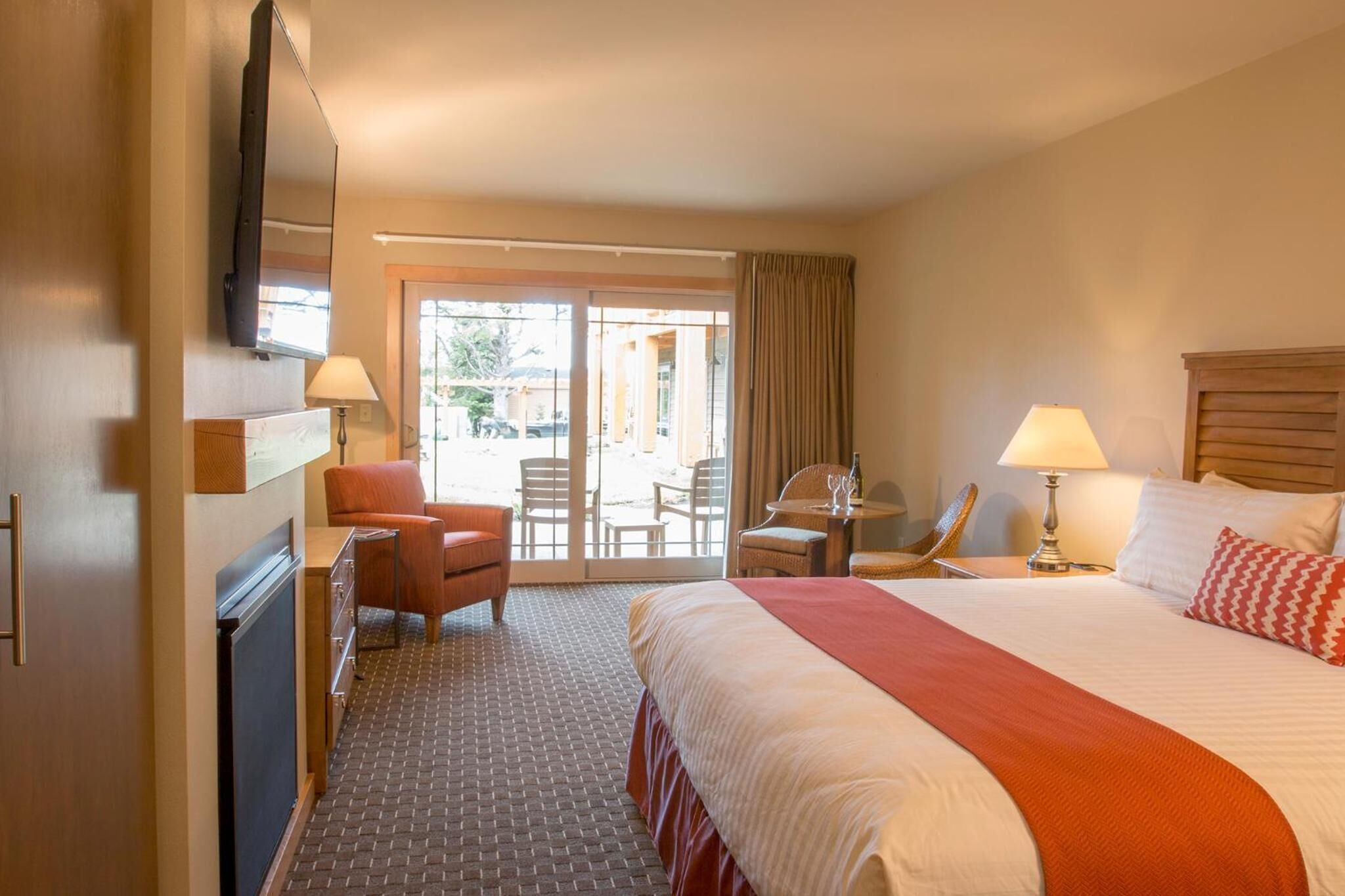 Une chambre d’hôtel avec un grand lit, un bureau avec une chaise, une petite table avec une chaise et un téléviseur fixé au mur.