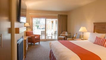 A hotel room with a large bed, a desk with a chair, a small table with a chair, and a TV mounted on the wall.