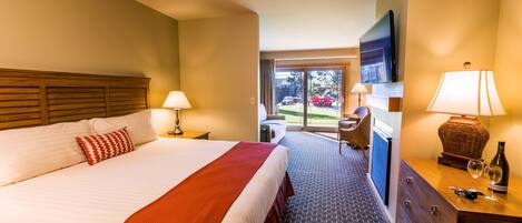 Habitación de hotel con una cama grande, un escritorio, una silla, un televisor y vistas al exterior.