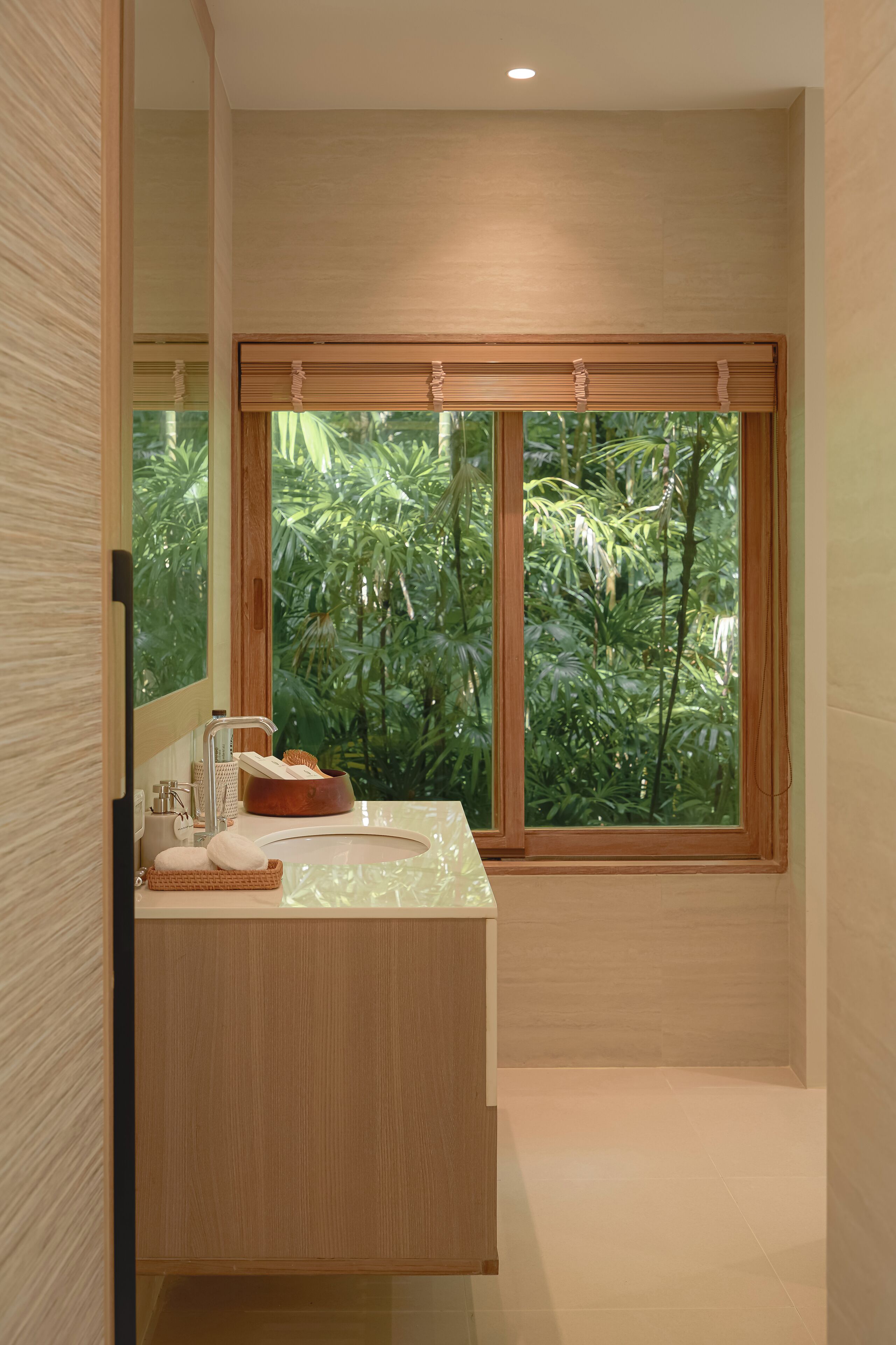 A modern bathroom with a large window, a wooden vanity, and a bathtub.