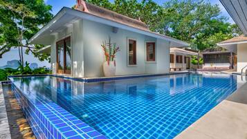 Una piscina al aire libre, sillones reclinables de piscina