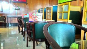 Un espace détente avec des fauteuils à revêtement vert et un comptoir en bois sur lequel est affiché le menu.