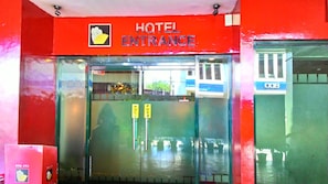 En hotellentrél med en röd skylt, en glasdörr och två handtag som man kan trycka eller dra i för att öppna dörren.