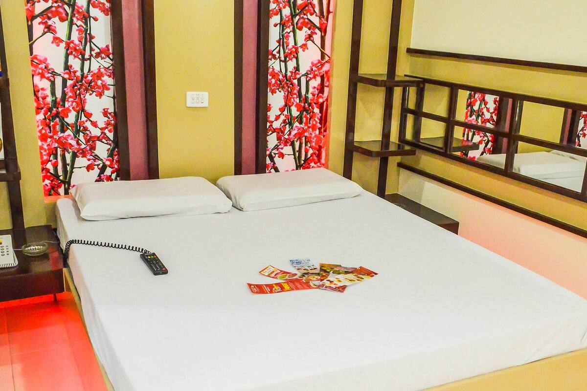 Een hotelkamer met een bed, nachtkastje met telefoon en plank met menukaart en betaalpas-pictogram.