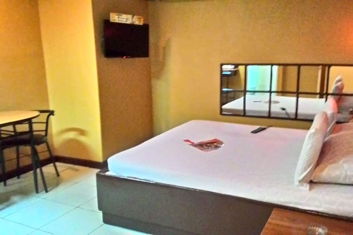 Een hotelkamer met een bed, een bureau en een televisie aan de muur.