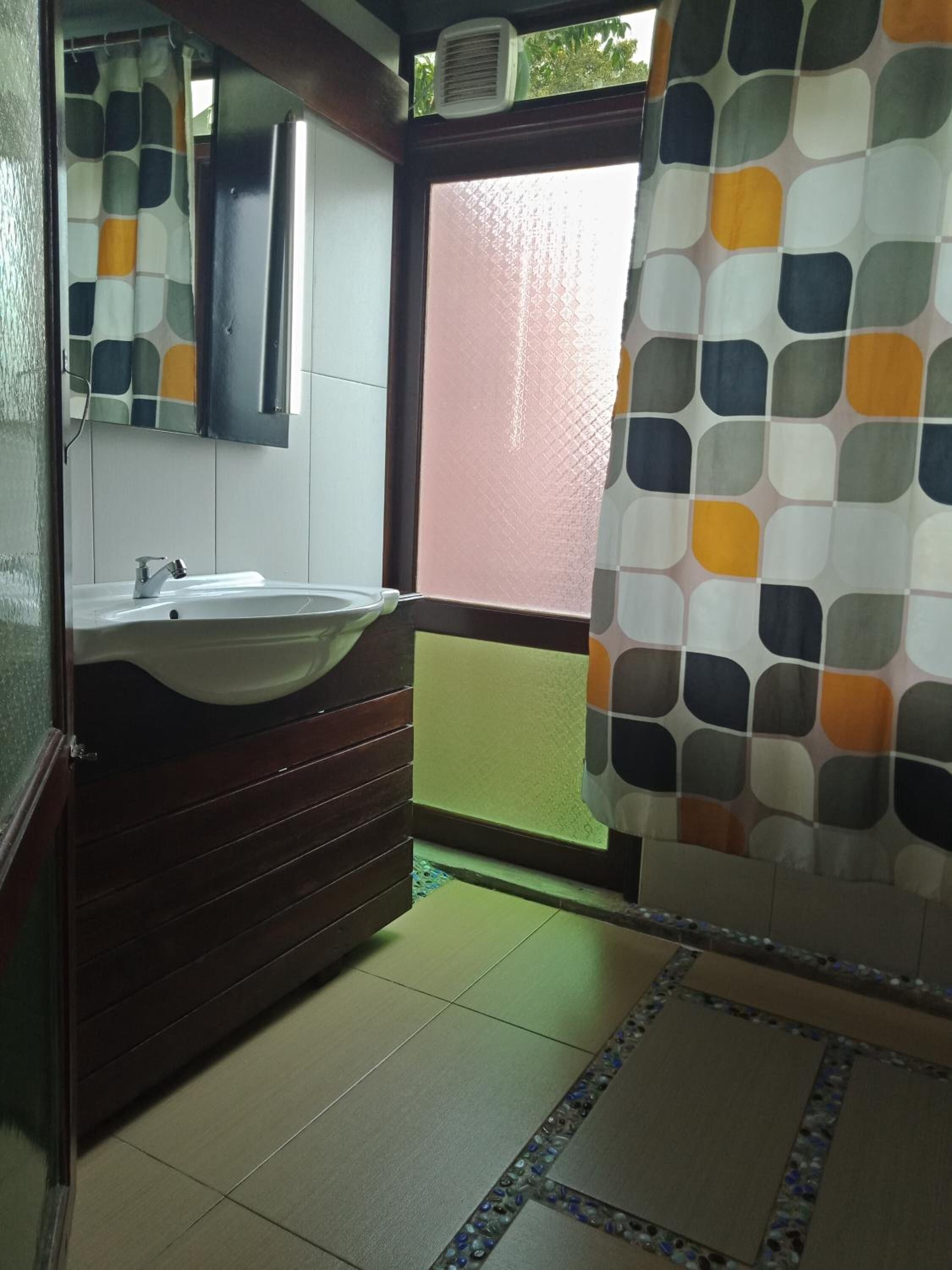 A bathroom with a sink, mirror, and a shower curtain with a geometric pattern.