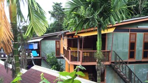 A multi-story building with balconies, a staircase, and surrounding greenery. - T Star Cottage (Langkawi)