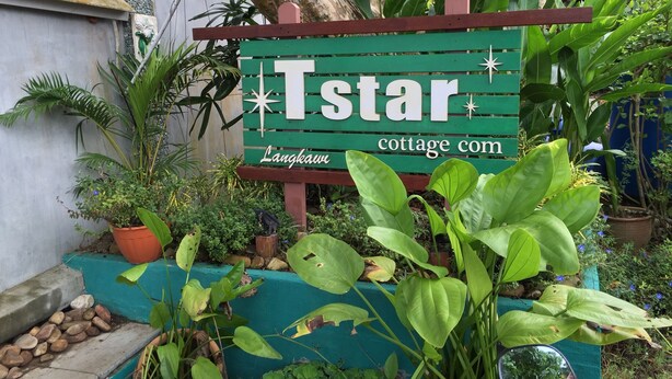 A sign for 'Tstar' cottage with a star decoration, surrounded by lush greenery and a tree. - T Star Cottage (Langkawi)