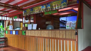 A reception area with a wooden counter, a clock, and a sign indicating the reception. - T Star Cottage (Langkawi)