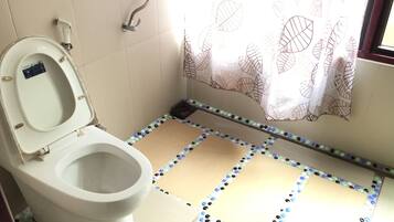 Une salle de bain équipée de toilettes, d’une douche et d’un rideau de douche à motifs.