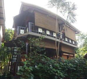 A multi-story building with a curved roof, balconies with railings, and a mix of glass and wooden elements. - T Star Cottage (Langkawi)