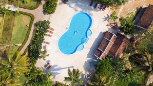 An aerial view of a swimming pool surrounded by palm trees and lounge chairs. - Santi Resort & Spa (Luang Prabang)