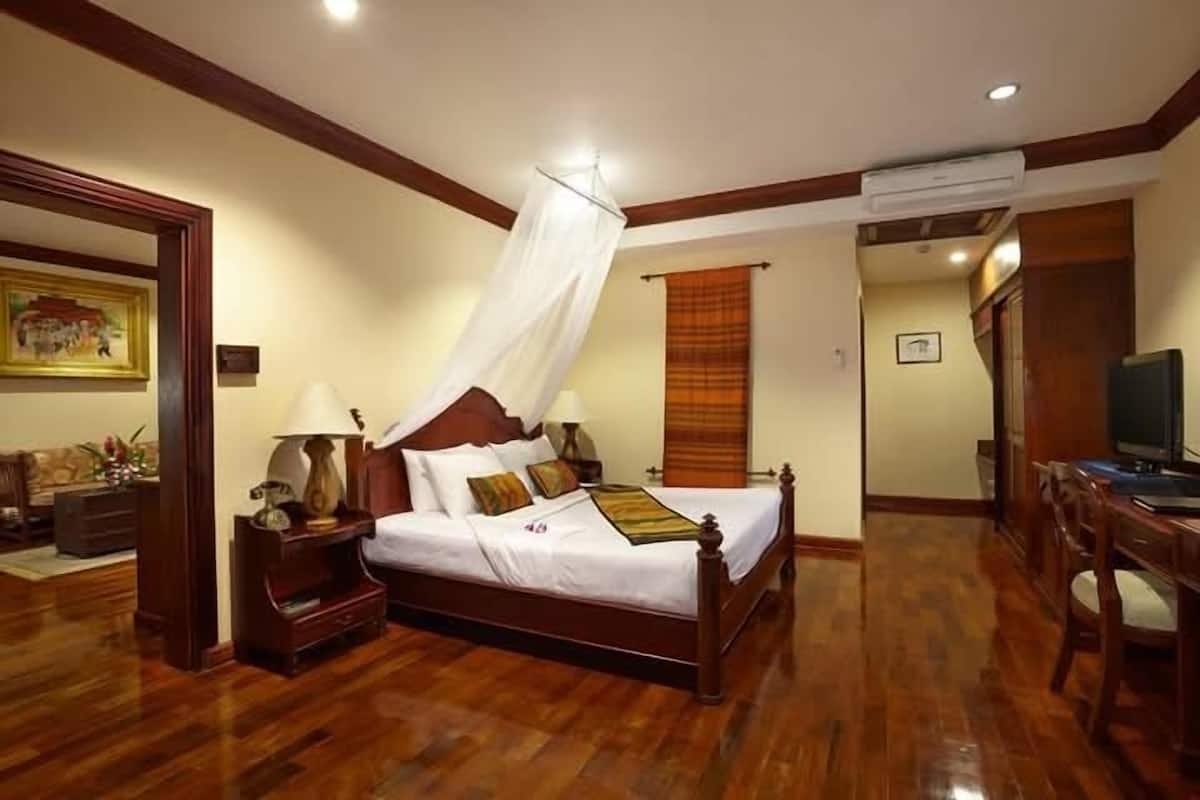 A neatly arranged bedroom with a wooden bed, a nightstand, a bedside table, and a television.