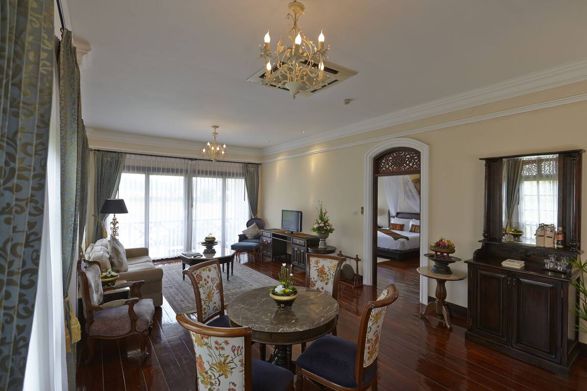 A spacious living room with a dining area, a television, and a large mirror.