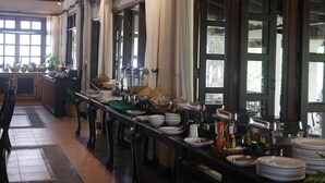 A buffet setup with a long table, various food items, and condiments. - Santi Resort & Spa (Luang Prabang)