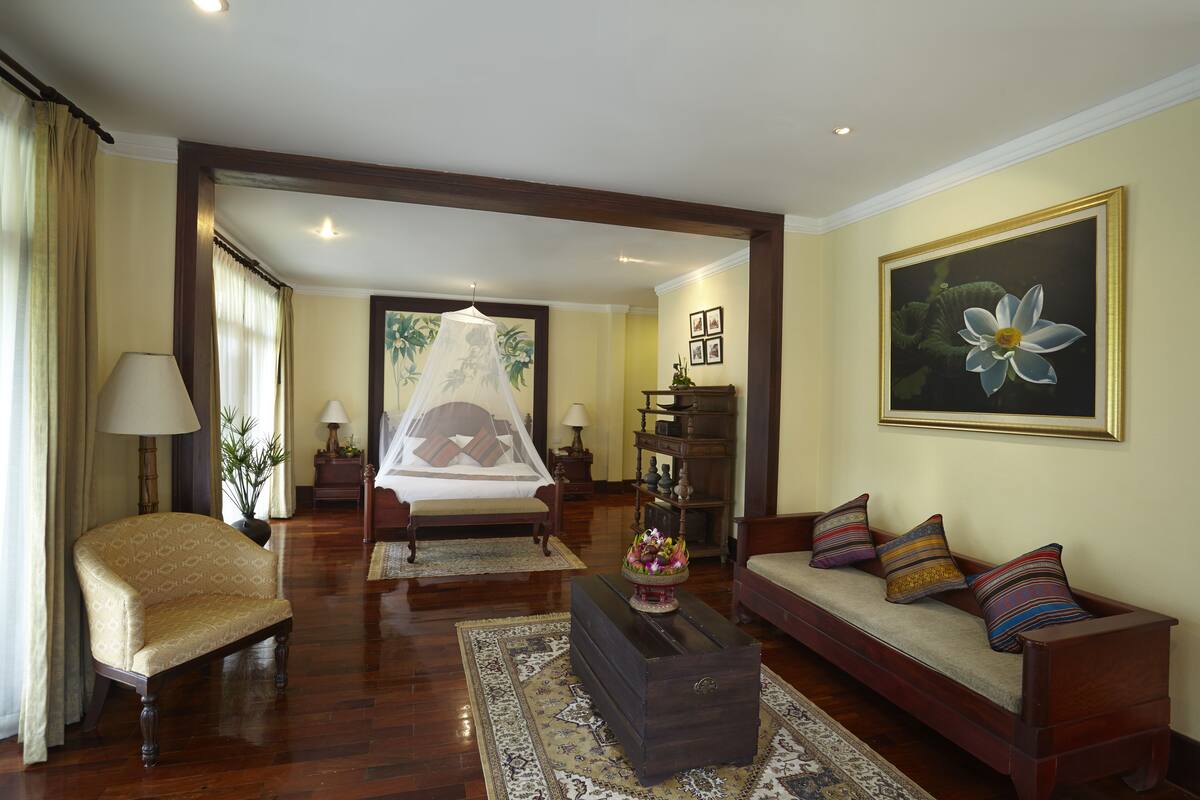 A spacious living room with a bed, a sofa, a chair, and a coffee table.