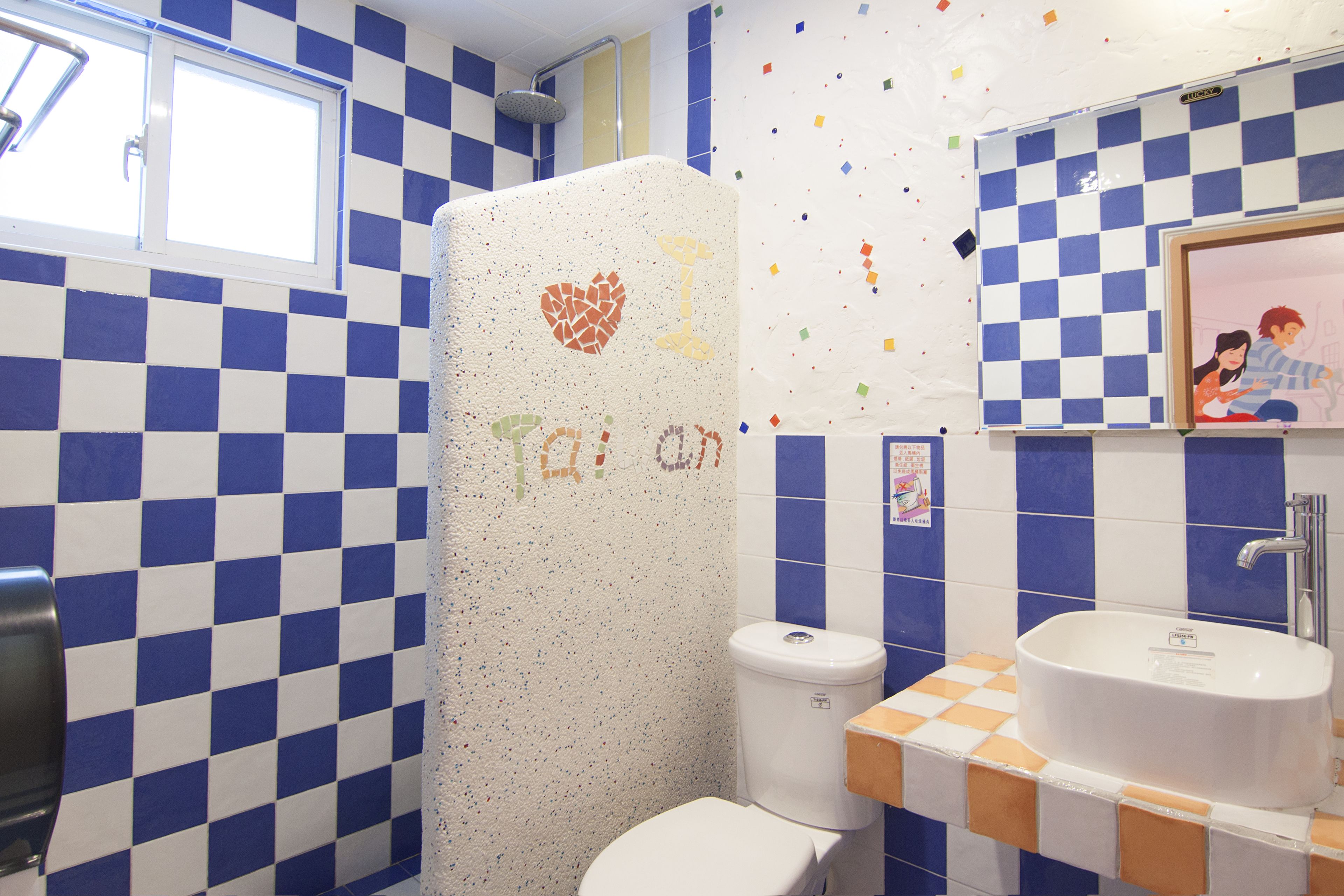 A bathroom with blue and white checkered tiles, a toilet, a sink, and a shower.