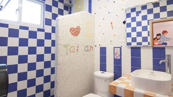 A bathroom with blue and white checkered tiles, a toilet, a sink, and a shower.