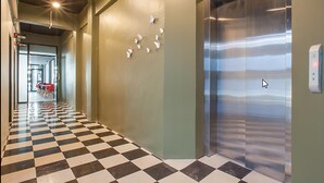 A hallway with a checkered floor, an elevator, and a wall with paper butterflies. - The Bed Hatyai (Hat Yai)