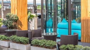 An outdoor seating area with wicker furniture and potted plants. - The Bed Hatyai (Hat Yai)