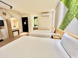 Une chambre d’hôtel avec deux lits, un petit bureau, une télévision et un mur vert.