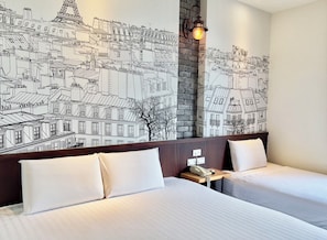 Habitación de hotel con dos camas, una pared decorada con ladrillos y un mural de paisaje urbano.