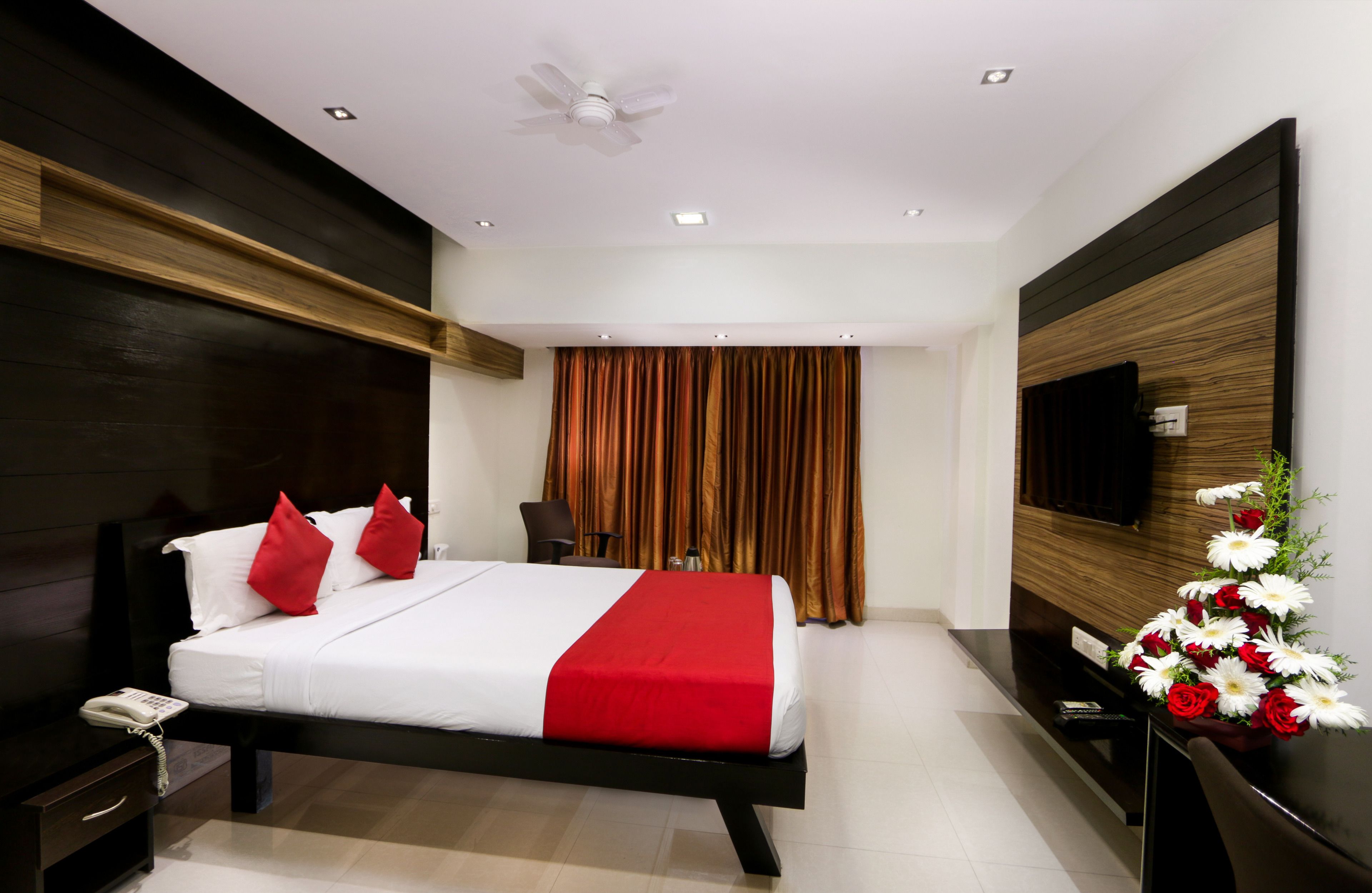 A modern hotel room with a bed, bedside table, and a TV on the wall.