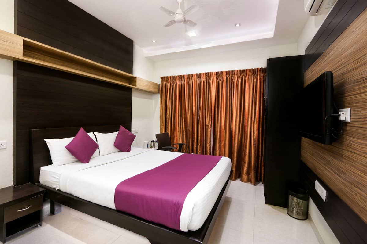 A modern hotel room with a large bed, a TV mounted on the wall, and a ceiling fan.