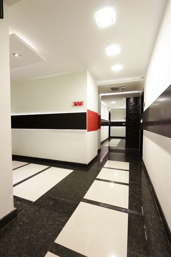 A modern hotel corridor with a check-in desk, a fire alarm, and a staircase.